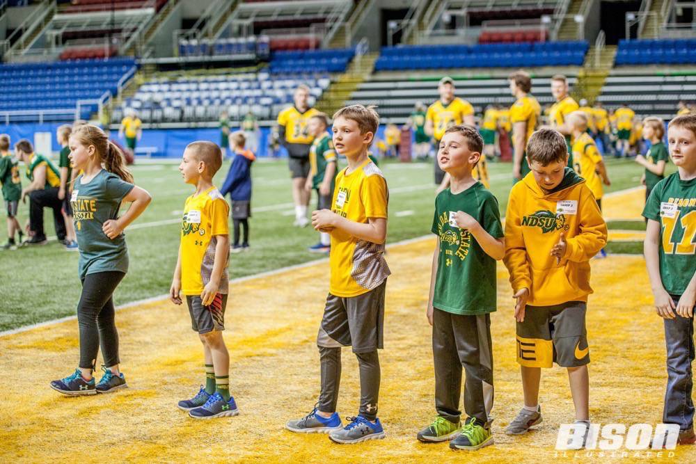 Kids watch the football players practice at the Bison summer camps