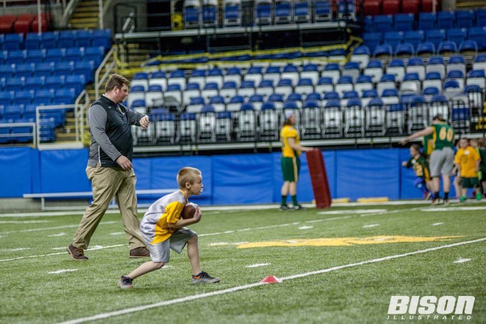 A boy catches the football during the Bison summer camp